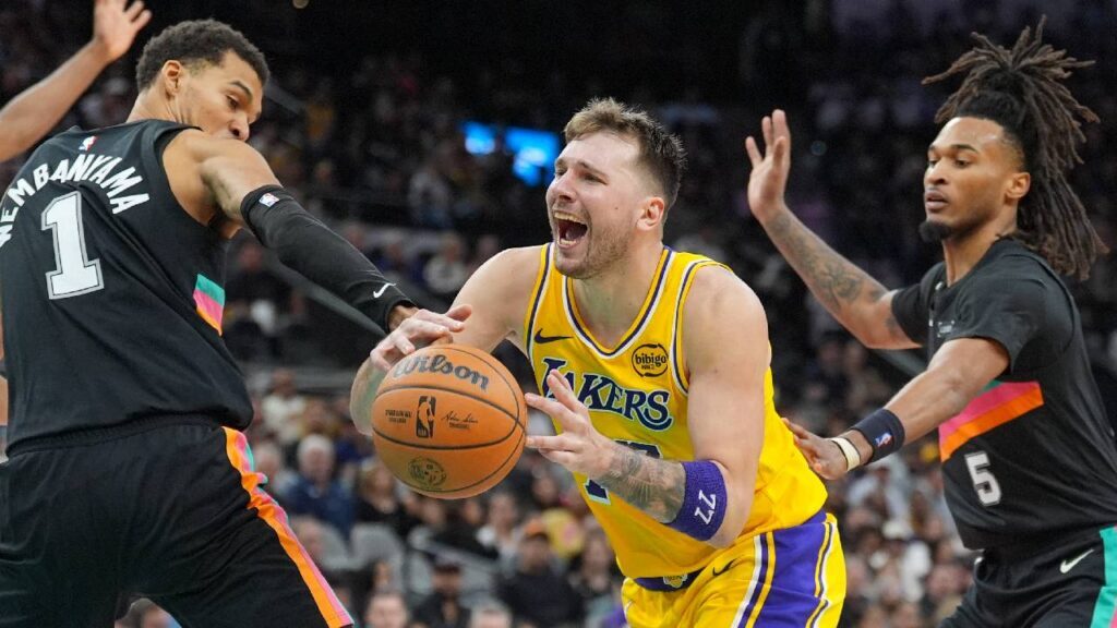 Los Angeles Lakers forward/guard Luka Dončić (77) draws a foul in between San Antonio Spurs forward/center Victor Wembanyama (1) and guard Stephon Castle (5) in the second half at Frost Bank Center.