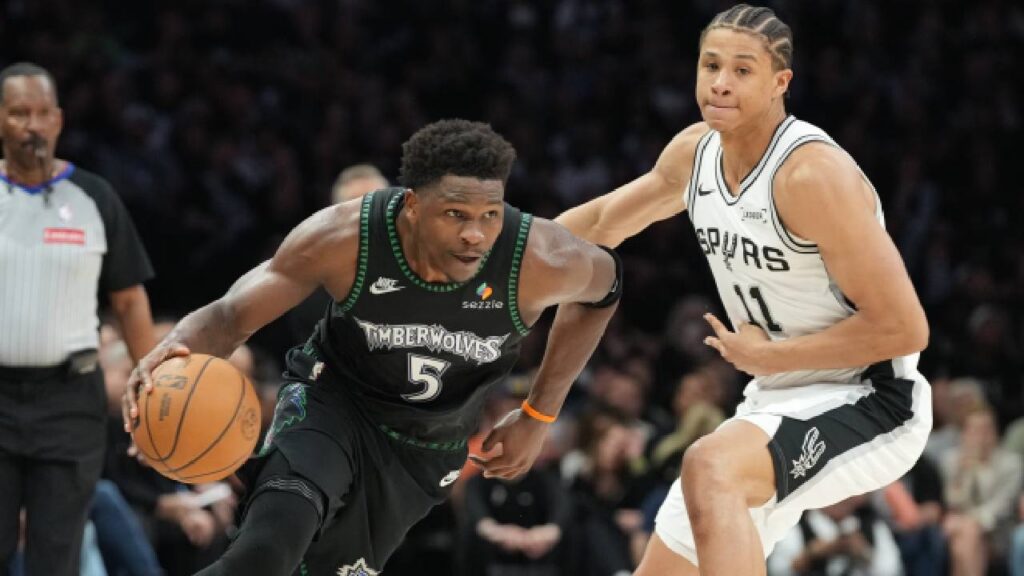 Minnesota Timberwolves guard Anthony Edwards (5) dribbles the ball past San Antonio Spurs forward Carter Bryant (11) in the second half during game six of the second round of the 2026 NBA Playoffs at Target Center.