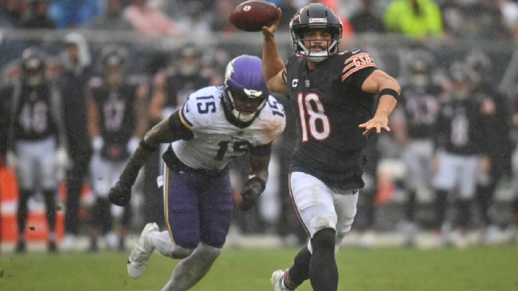 Chicago Bears quarterback Caleb Williams (18) scrambles and throws a pass against Minnesota Vikings linebacker Dallas Turner (15) during the second half at Soldier Field before the Caleb Williams Injury update.