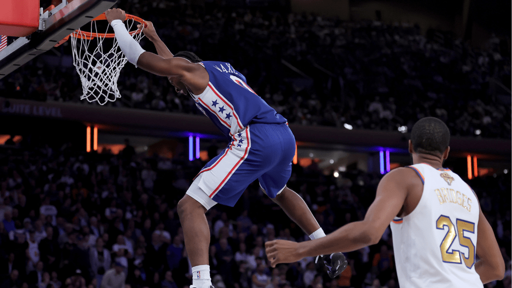 Oct 20, 2026; New York, New York, USA; Philadelphia 76ers guard Tyrese Maxey (0) hangs on the rim after a dunk against New York Knicks guard Mikal Bridges (25) during the fourth quarter at Madison Square Garden. Mandatory Credit: Brad Penner-Imagn Images