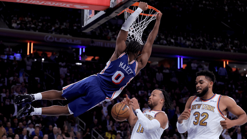 Oct 20, 2026; New York, New York, USA; Philadelphia 76ers guard Tyrese Maxey (0) hangs on the rim after a dunk against New York Knicks guard Jalen Brunson (11) and center Karl-Anthony Towns (32) during the fourth quarter at Madison Square Garden. Mandatory Credit: Brad Penner-Imagn Images