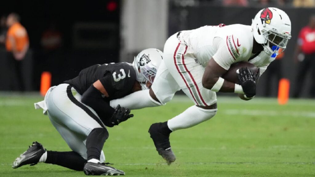 Arizona Cardinals running back Jeremiyah Love (4) carries the ball against Las Vegas Raiders cornerback Taron Johnson (3) in the first half at Allegiant Stadium.