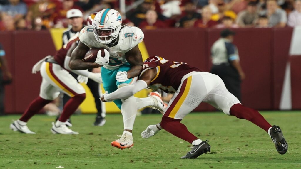 Aug 14, 2026; Landover, Maryland, USA; Miami Dolphins running back Ollie Gordon II (0) runs with the ball as Washington Commanders cornerback Car'lin Vigers (37) makes a tackle during the second half at Northwest Stadium. Mandatory Credit: Geoff Burke-Imagn Images