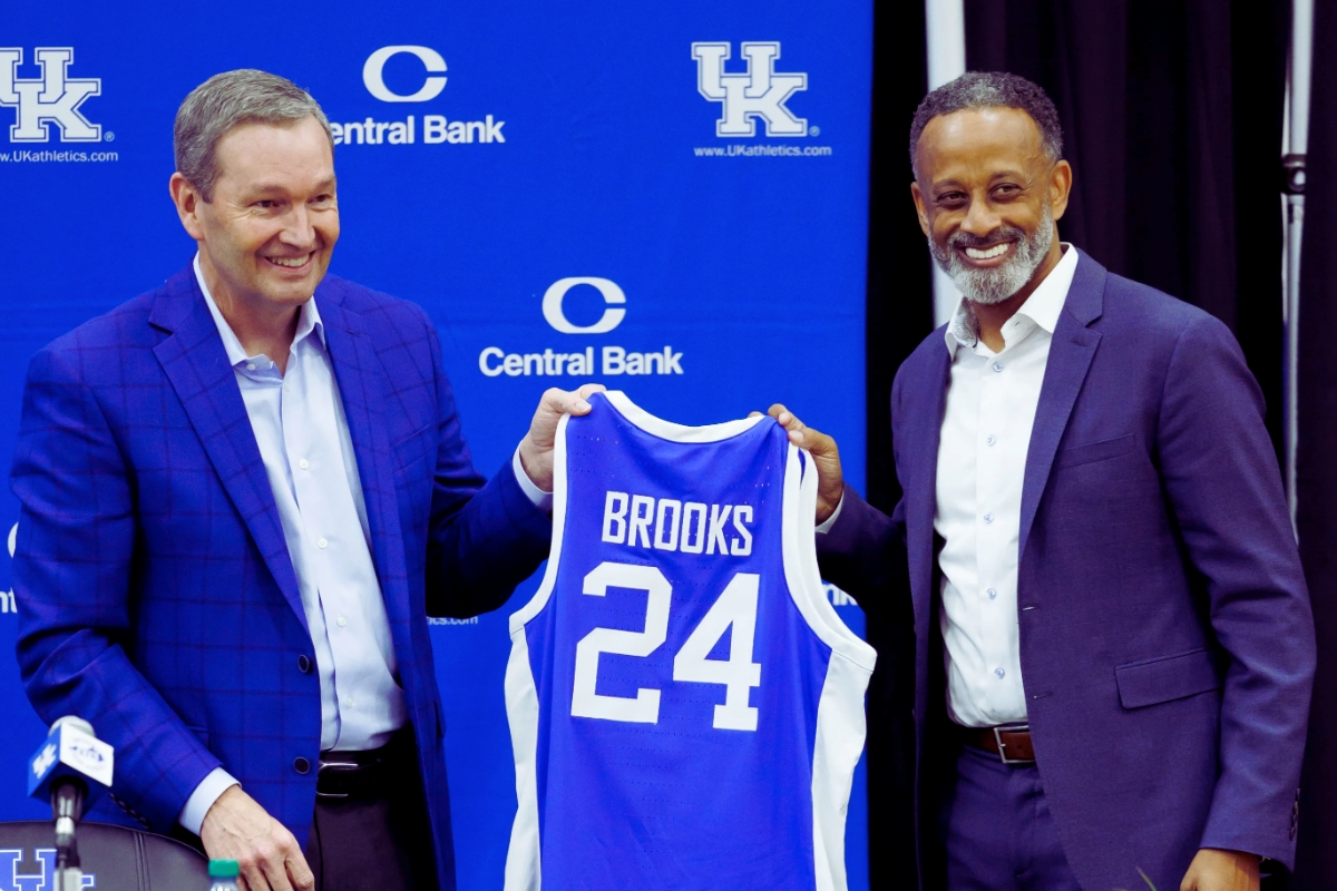 Kentucky Wildcats basketball jersey with the name "Brooks" and the number 24 on the back, standing in front of a UK Athletics and Central Bank backdrop.
