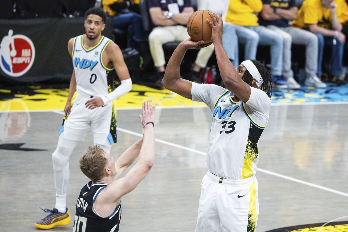 Myles Turner of the Indiana Pacers shoots over a Milwaukee Bucks player as Tyrese Haliburton watches in the background.