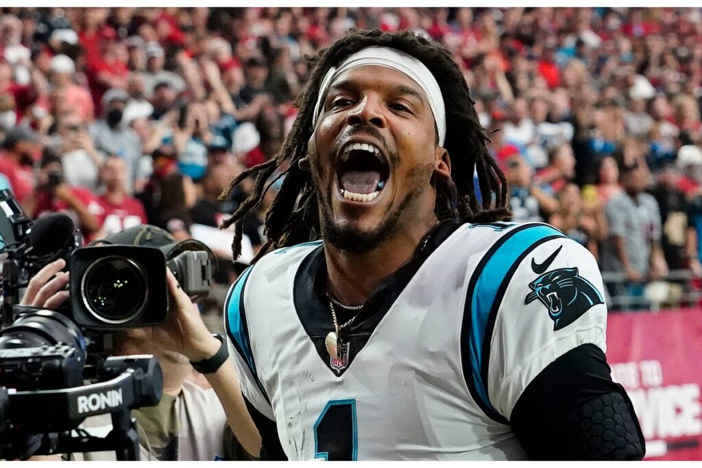 Carolina Panthers quarterback Cam Newton yells \"I'm back!\" after scoring a rushing touchdown against the Arizona Cardinals in a game in 2021.