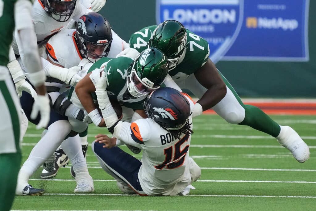 New York Jets quarterback Justin Fields (7) is tackled by Denver Broncos linebacker Nik Bonitto (15) during an NFL International Series game at Tottenham Hotspur Stadium.