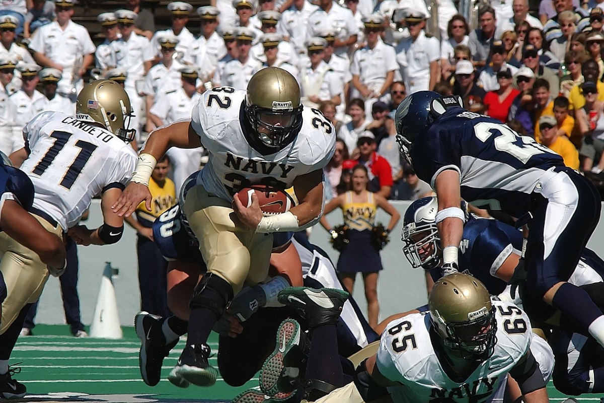 College Football game. Navy running back running the ball.