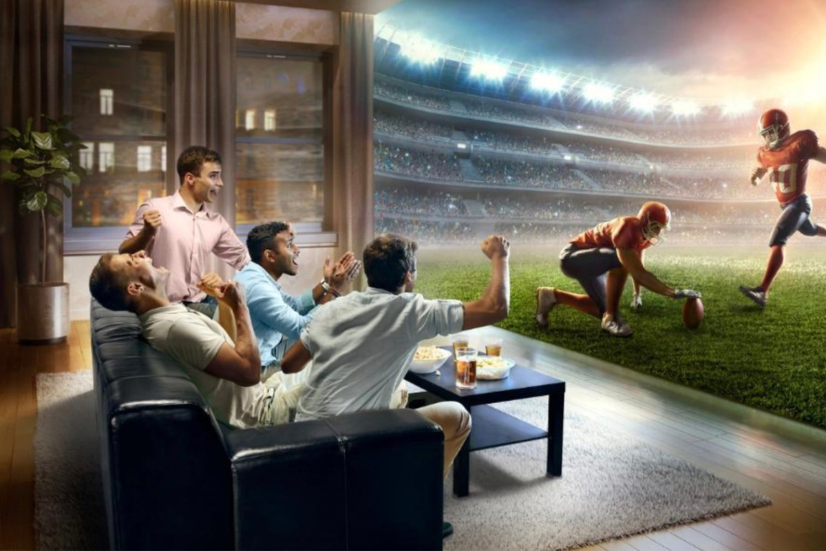 People watching a game on the couch while also being close to an NFL kicker. Stadium seats vs. the couch experience: which is the best way to view games?