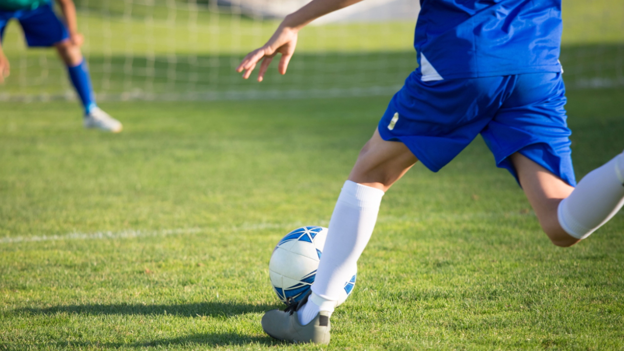 Soccer player running and kicking the ball.