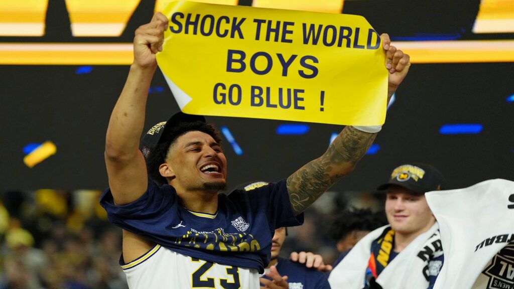 2026 NBA Draft 11th overall pick Yaxel Lendeborg holding "Shock The World Boys Go Blue!" sign after National Championship win.