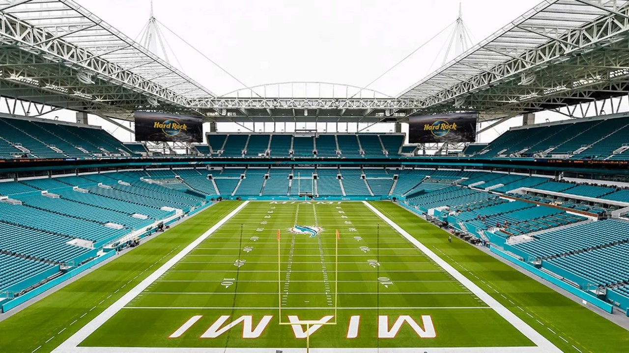 Hard Rock Stadium during a Miami Dolphins game, featuring the Dolphins logo at midfield and the “MIAMI” end zone.