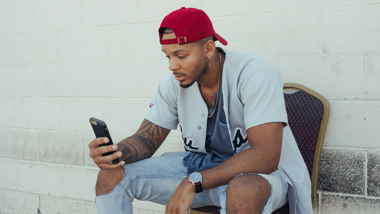 Sports fan checking his phone during the 2026 summer sports draught.