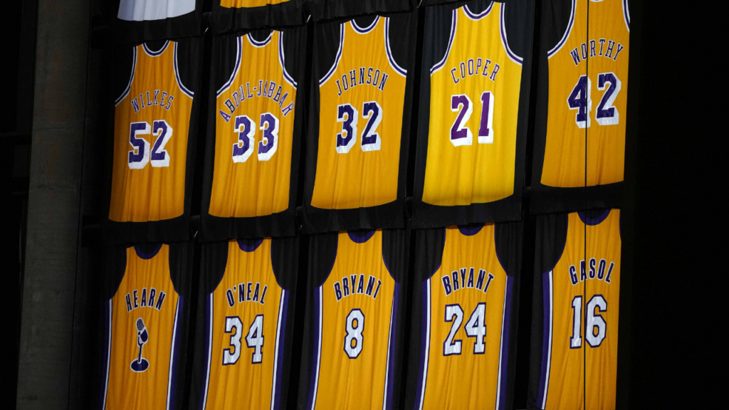 Mar 3, 2026; Los Angeles, California, USA; The retired jerseys of Los Angeles Lakers players Jamaal Wilkes (52), Wilt Chamberlain (13), Elgin Baylor (22), Shaquille O'Neal (34), Jerry West (44), Magic Johnson (32), James Worthy (42), Kareem Abdul-Jabbar (33), Kobe Bryant (8 and 24) and Chick Hearn and the names of Minneapolis Lakers Hall of Fame players Vern Mikkelsen, George Mikan, Jim Pollard, Slater Martin, John Kundla and Clyde Lovellette at the Crypto.com Arena. Mandatory Credit: Kirby Lee-Imagn Images. Kushner. 